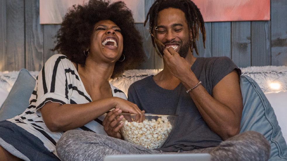 Connect with loved ones during the lockdown couple laughing eating popcorn